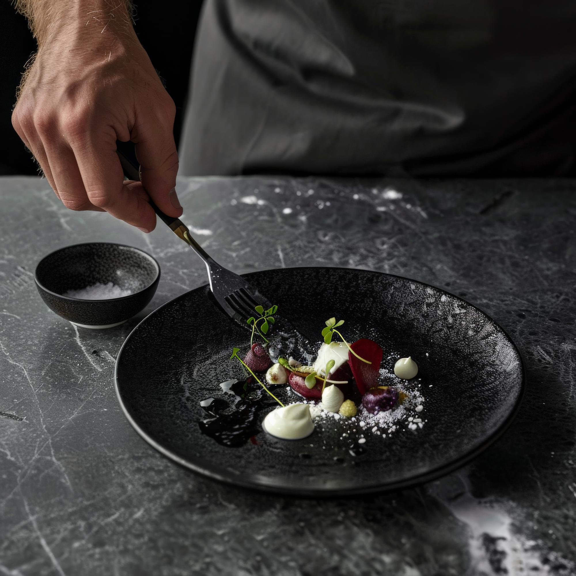 chef arranging plated gourmet dish on slate